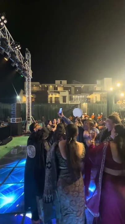 An open-air crowd dancing at night in front of the stage.