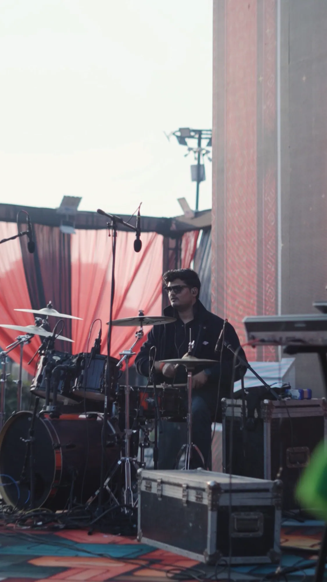 Softrock's drummer at the kit during a daytime soundcheck, red drapes behind.