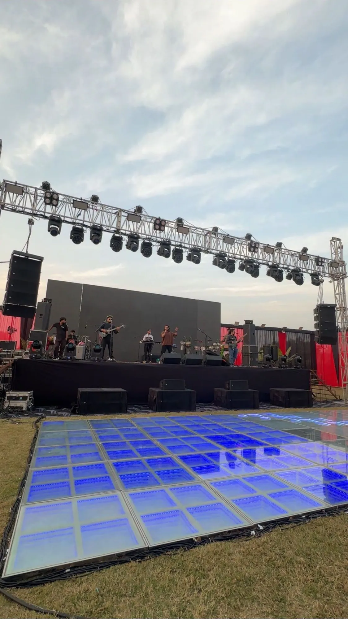 Softrock's open-air stage and lighting truss set up in daylight, with an LED dance floor in front.